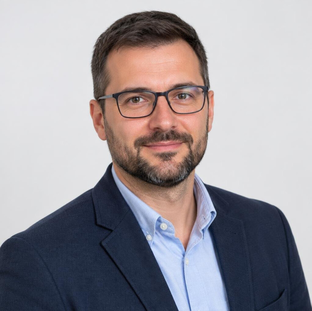 Studio portrait of a bearded man with glasses in business casual attire