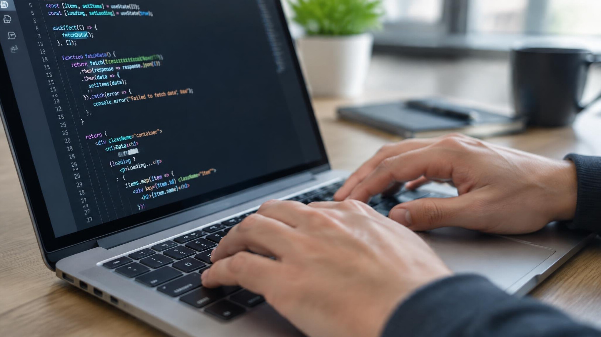 Close-up of hands typing on a laptop keyboard with code on screen